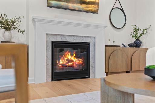 A beautifully appointed fireplace with classic marble detail and warm glowing ambiance. The perfect place to unwind on a cool evening.