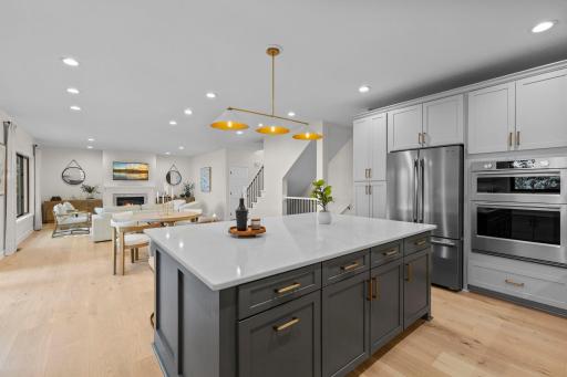 Another angle of the chef's kitchen showcasing the custom cabinetry, high-end appliances, and the open flow into the main living area.