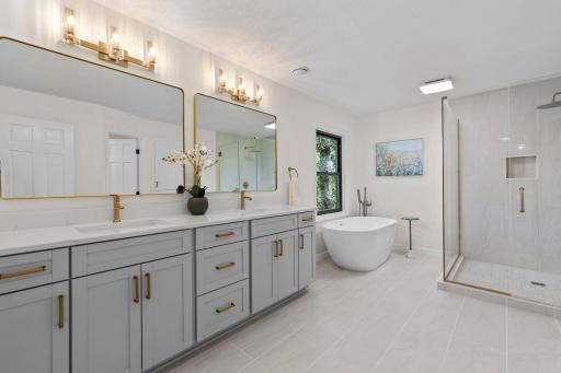 Stunning primary bathroom with a freestanding soaking tub, dual vanity, oversized mirror, and a serene, spa-inspired design from top to bottom.