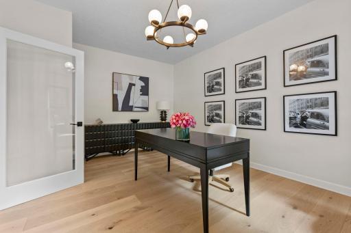 Sophisticated home office with designer lighting, gallery wall, and ample workspace. A perfect setup for working from home in style.
