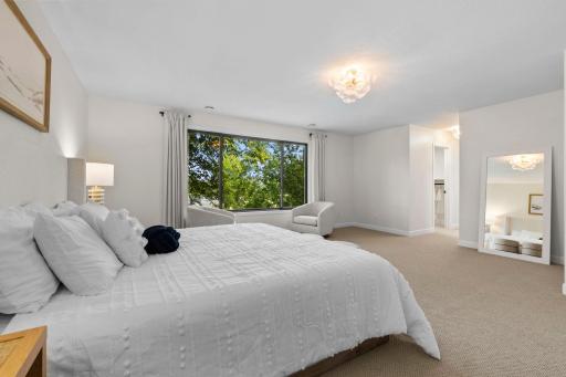 Serene primary bedroom retreat with plush carpeting, large windows framing the wooded views, and a peaceful, light-filled atmosphere.