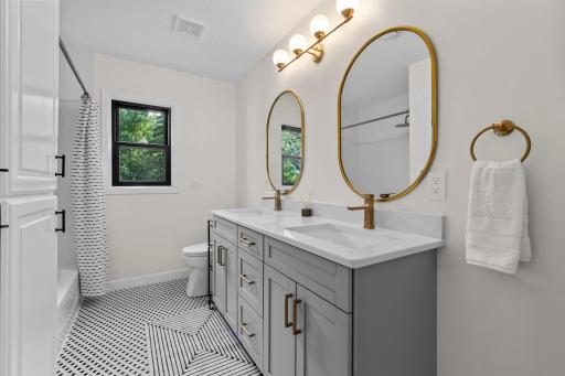Gold oval mirrors, designer fixtures, and a beautifully tiled floor for a polished, upscale feel.