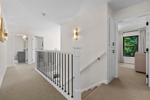 Elegant staircase with wrought iron balusters, crisp white trim, and designer sconce lighting leading to the upper level.