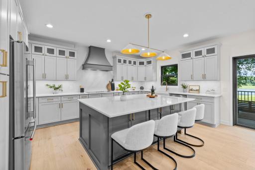 Chef's kitchen featuring a large center island, custom cabinetry, premium appliances, and a statement range hood. Designed for both everyday living and entertaining.