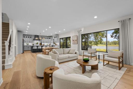 Spacious great room with an open-concept layout, abundant natural light, and seamless flow to the outdoor deck and lake beyond.