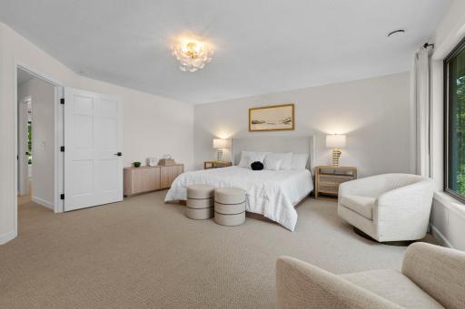 Another angle of the primary suite showcasing the spacious layout, cozy sitting area, and the natural light that fills every corner of the room.