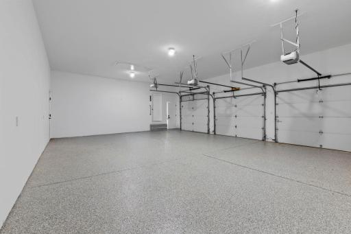 Second view of the spacious three-car garage showcasing the generous depth, clean finish, central vacuum (for easy car cleanouts)and multiple overhead doors.