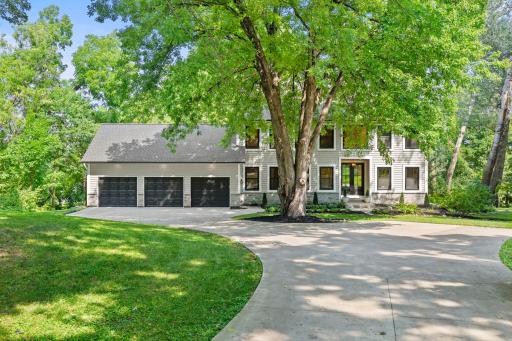 Welcoming front exterior with a sweeping circular driveway, mature trees, and a timeless facade that makes a lasting first impression.