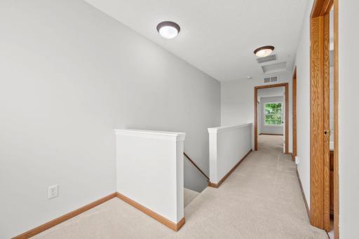 The upper level opens to a bright hallway connecting the bedrooms, full bath, and laundry