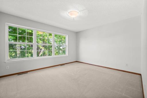 Spacious primary bedroom with a wall of windows bringing in beautiful natural light and peaceful views of the mature trees