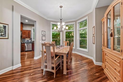 Formal dining room surrounded by windows and warm walnut hardwood floors.