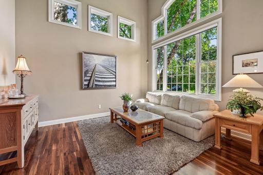 Sun-filled living room with soaring windows overlooking the wooded setting.