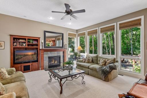 Inviting family room with gas fireplace and walls of wooded views.