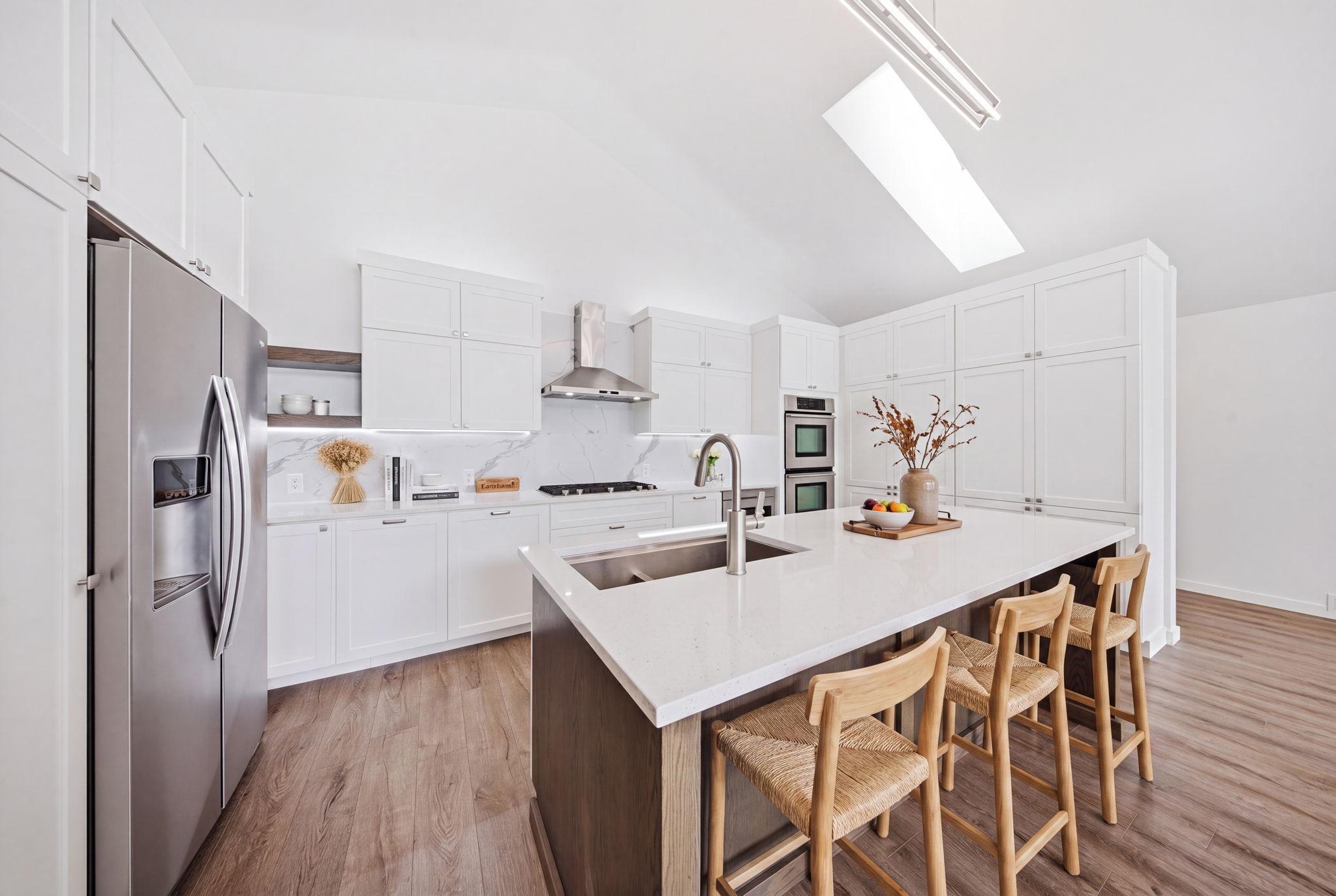 The modern kitchen features stainless steel appliances, a spacious center island, and abundant counter and cabinet space. (virtually staged)