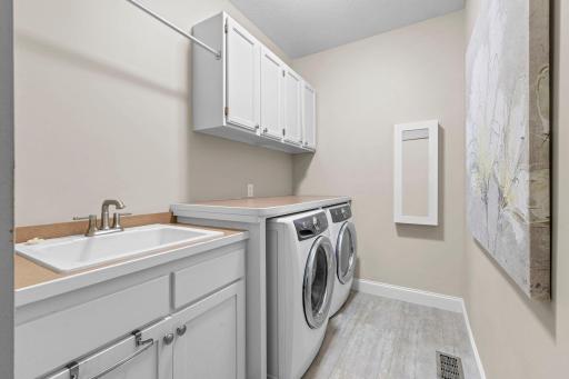 Functional laundry room with built-in cabinets, folding counter, and hanging rack.