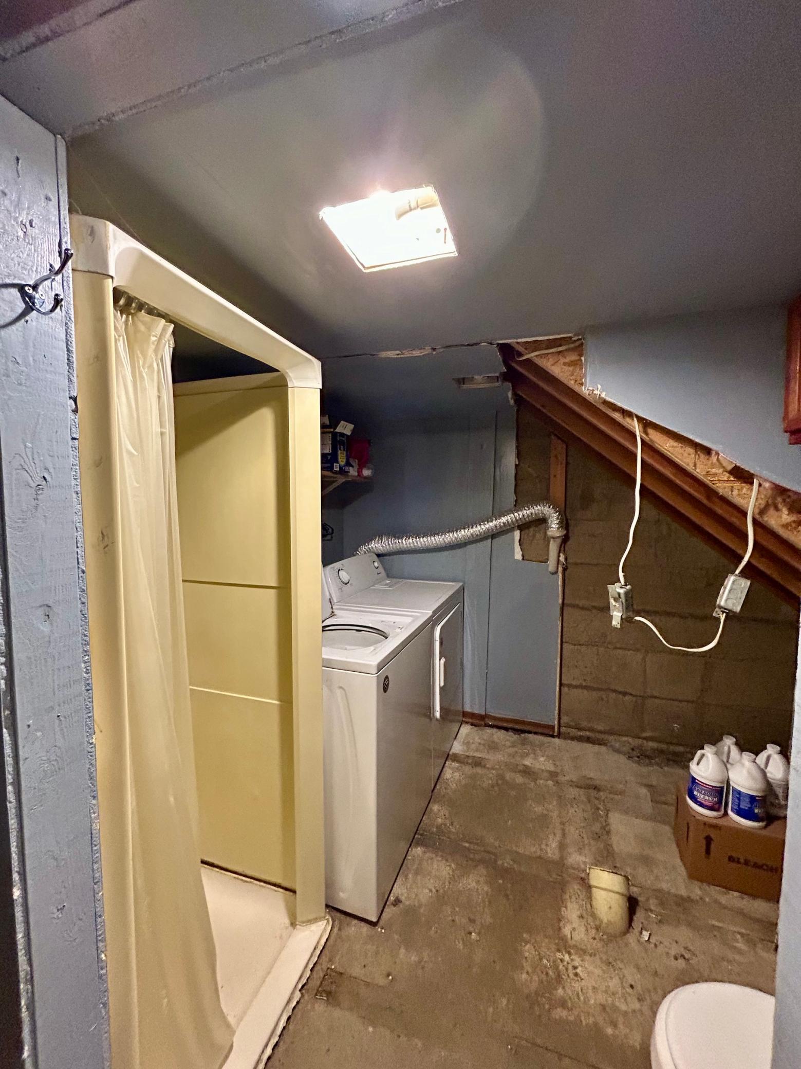 Washer and dryer in basement with shower and toilet