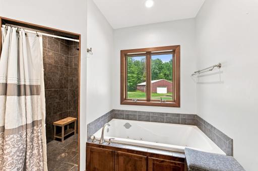 Primary en suite featuring dual sinks, jacuzzi tub, and tiled walk in shower