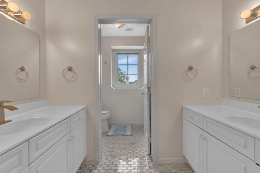 Upper-level full bathroom featuring dual vanities and private toilet area.