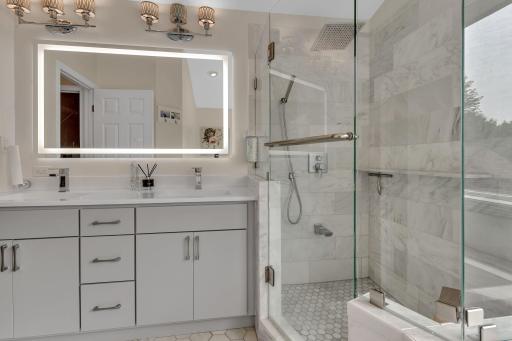 Newly remodeled primary bathroom with luxury marble tile, vanity, and mirror.
