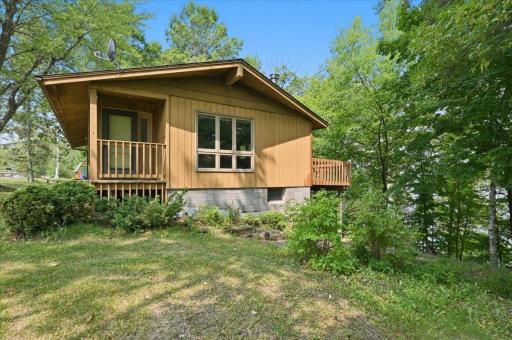 Mid-century modern style with a nice covered front porch entrance, a large deck facing the lake, updated retaining walls and landscaping that will look great with some freshening up.
