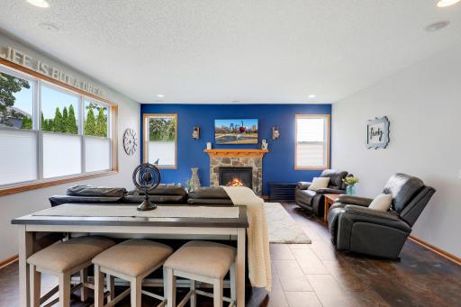 Bright and inviting living room featuring large windows, ample natural light, and a cozy gas fireplace as the focal point.