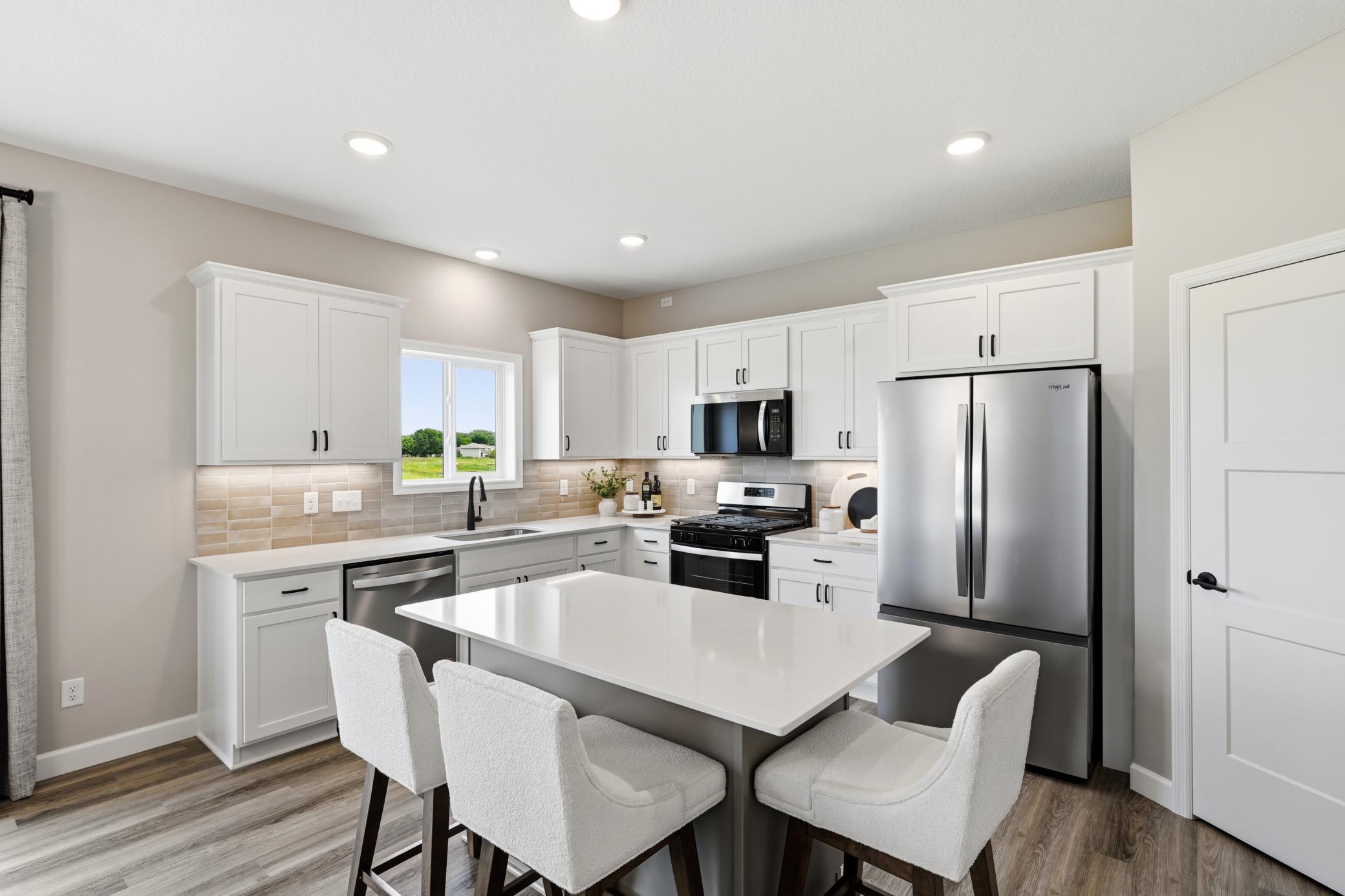 Highlights: under cabinet lighting, island, kitchen sink window, tile backsplash - photos of a staged, completed model, of the same floorplan for illustrative purposes.