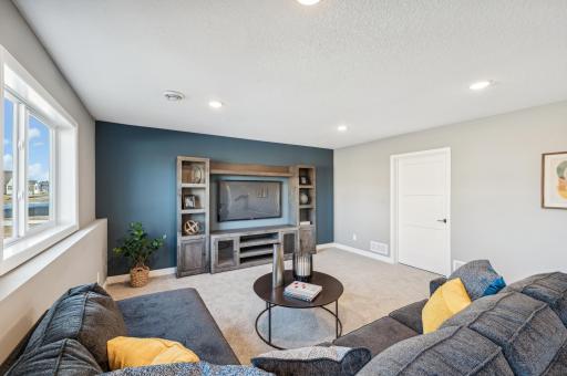 Finished lower level family room -photo is of a staged model home of the same floorplan. Selections and colors may differ.