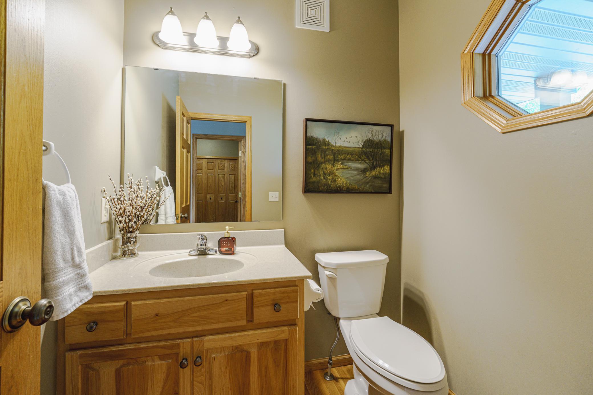 The powder bathroom features hardwood flooring and a hickory vanity.