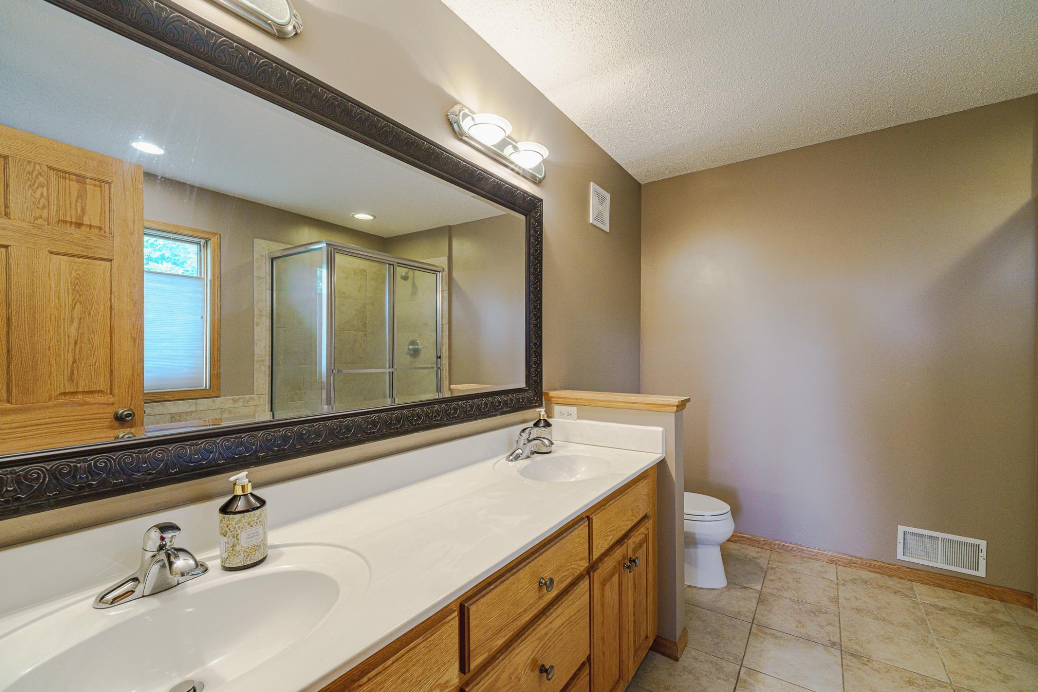 The full primary bath has dual sinks with a decorative mirror, a jetted tub, a separate walk-in shower, and a large window.