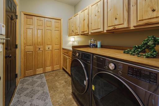 Adjacent to the powder bath is the laundry room, with tile flooring, a utility sink, folding counter, and newer washer and dryer.