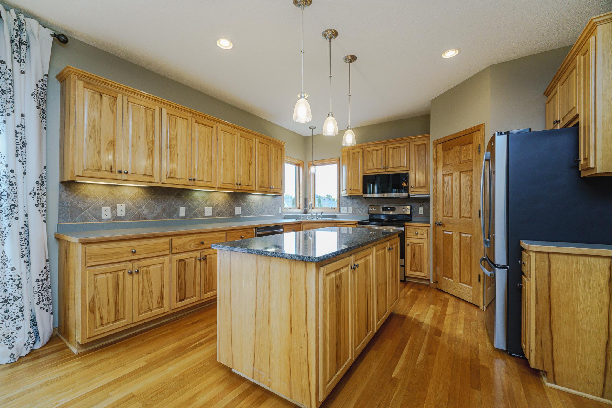 The kitchen features hickory cabinetry with undercabinet lighting, an oversized island with granite counters and pendant lighting.