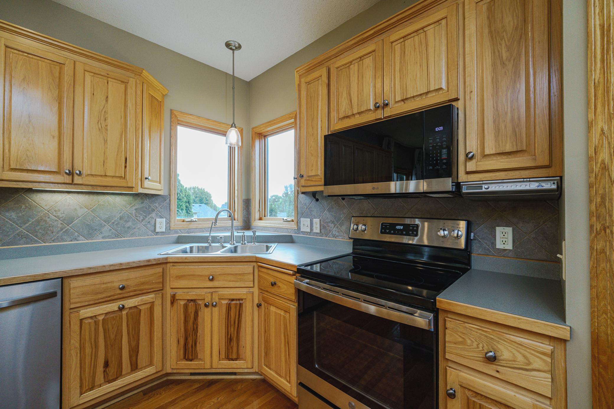 Corner windows above the sink let in the morning light. REAL hardwood flooring runs through the kitchen and partners with solid panel doors.