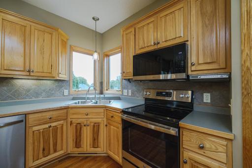 Corner windows above the sink let in the morning light. REAL hardwood flooring runs through the kitchen and partners with solid panel doors.