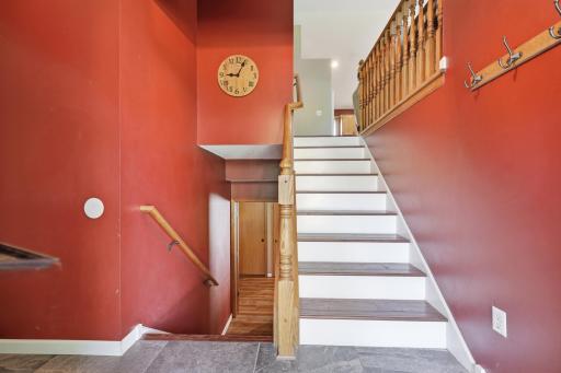 A split staircase with warm oak railings and slate tile flooring makes a striking first impression in the foyer. Rich wood accents and an open sightline to the upper level add character right at the entry.