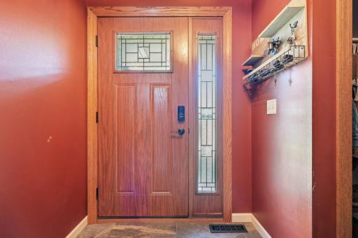 The oak front door with decorative glass panels brings natural light and warmth into the entryway. Durable flooring and a built-in coat and key nook add everyday function right where you need it.