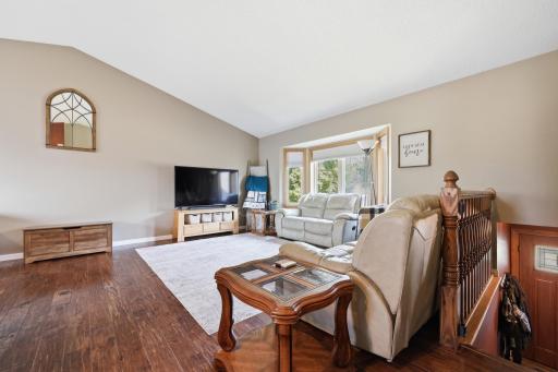 Vaulted ceilings and rich hardwood floors give this upper-level living room an open, airy feel. A bay window fills the space with natural light, while the open staircase connects easily to the rest of the home.