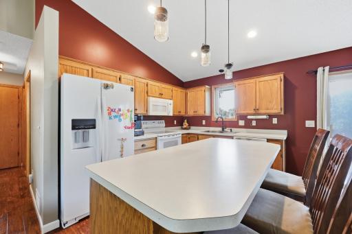 Warm oak cabinetry wraps the room while an oversized island provides plenty of prep space and room for barstools. The layout flows easily between the fridge, range, and sink for an efficient work triangle.