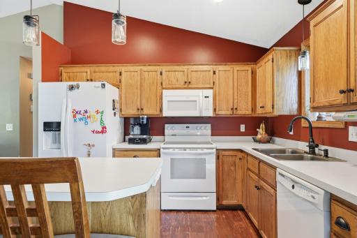 A deep stainless sink sits beneath a gooseneck faucet, offering a functional prep and cleanup zone with plenty of counter space nearby. The white appliances and warm cabinetry give this kitchen a timeless, classic look.