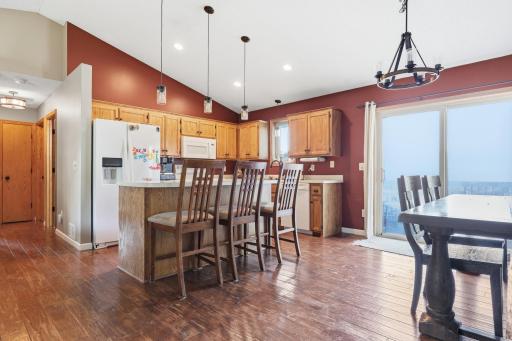 The kitchen opens directly into a dining area with sliding door access to the outdoors, perfect for easy indoor-outdoor entertaining. A statement chandelier over the dining table adds a stylish finishing touch.