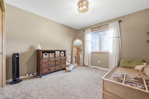 A bright upper-level bedroom offers soft carpet, generous closet space, and a large window for natural light. Neutral tones make it easy to picture as a guest room, office, or kids' space.