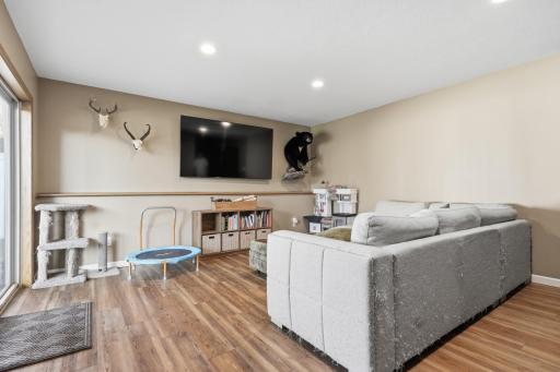 Plenty of room to spread out here, with wood-look flooring and neutral walls offering a versatile backdrop for however you like to unwind. Recessed lighting keeps the space bright even without natural light