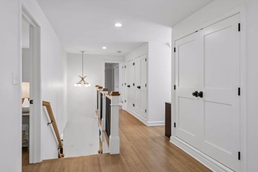 Upper level hallway with seamless, full-wall custom cabinetry providing discreet and expansive storage!