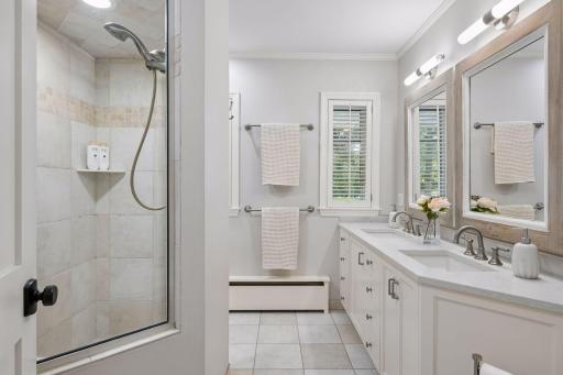 Primary bath with double vanity, fresh new lighting, cabinets, and a generous walk-in shower.