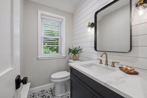 Beautifully appointed half-bath featuring crisp shiplap accents, a custom vanity and modern black hardware. Completely redesigned down to the stud walls.