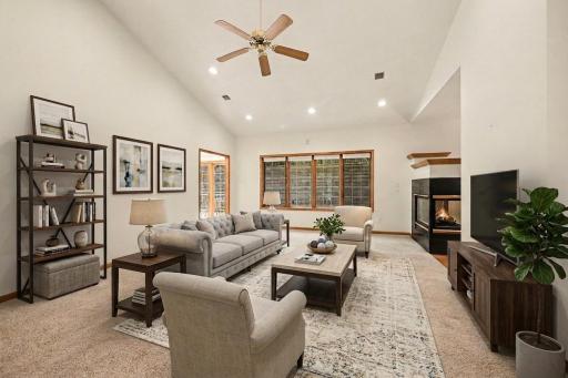 Vaulted main living room with large windows, gas fireplace, and open flow to the main level. (virtually staged to show potential)