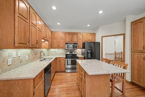 Bright kitchen featuring updated countertops, hardwood floors, and excellent cabinet storage.