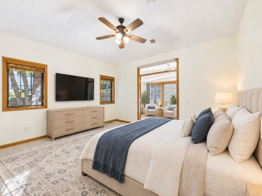Main-level primary bedroom staged to show the room's size and the connection toward the sunroom.