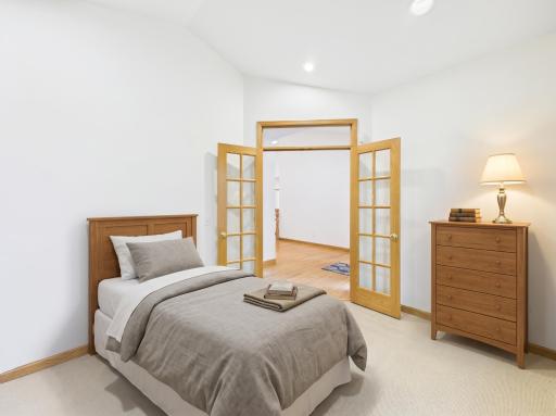 Main-level Bedroom/den with custom built-ins, virtually staged to show flexible office or guest-space potential.