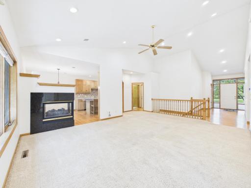 Vaulted main-level living room with gas fireplace, recessed lighting, and natural light.
