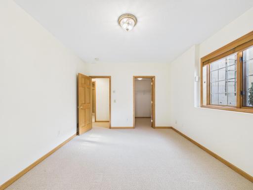 Finished lower-level bedroom with egress window and adjacent three-quarter bath access.